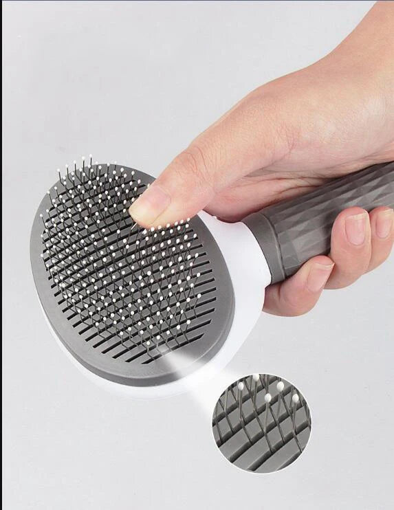 Pet grooming brush with gray round head and metal pins, finger pressing pins