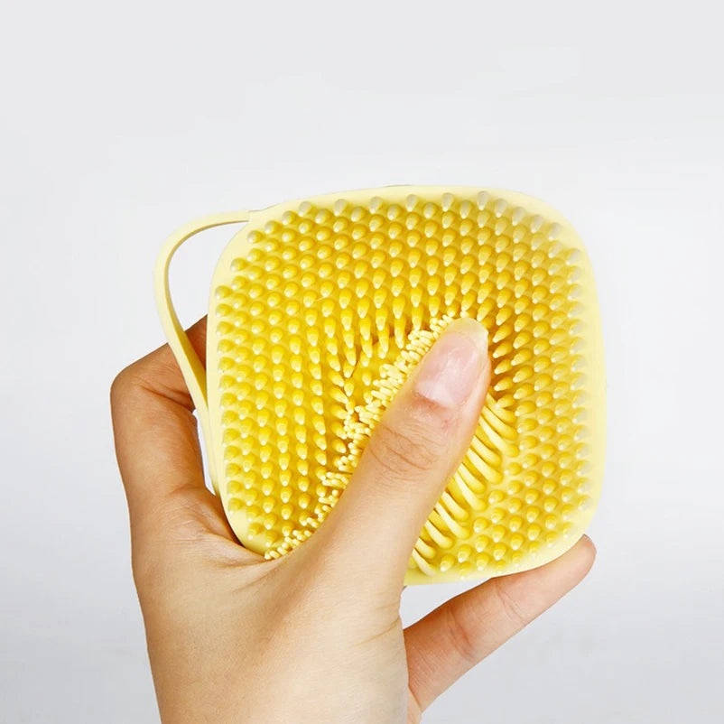 Yellow pet bath massage glove with spiky silicone massage surface in hand