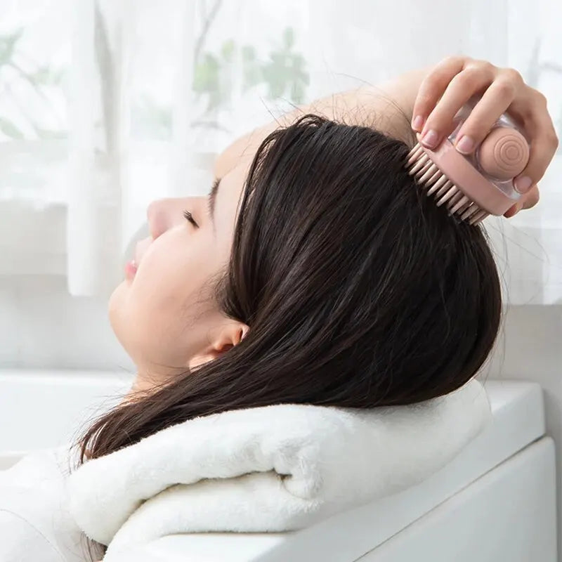 Pink silicone brush used on dark hair during bathing, held above head