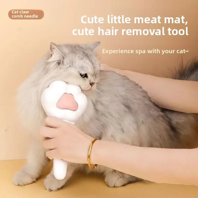 White pet grooming brush with pink paw comb head, used by hand on a cat